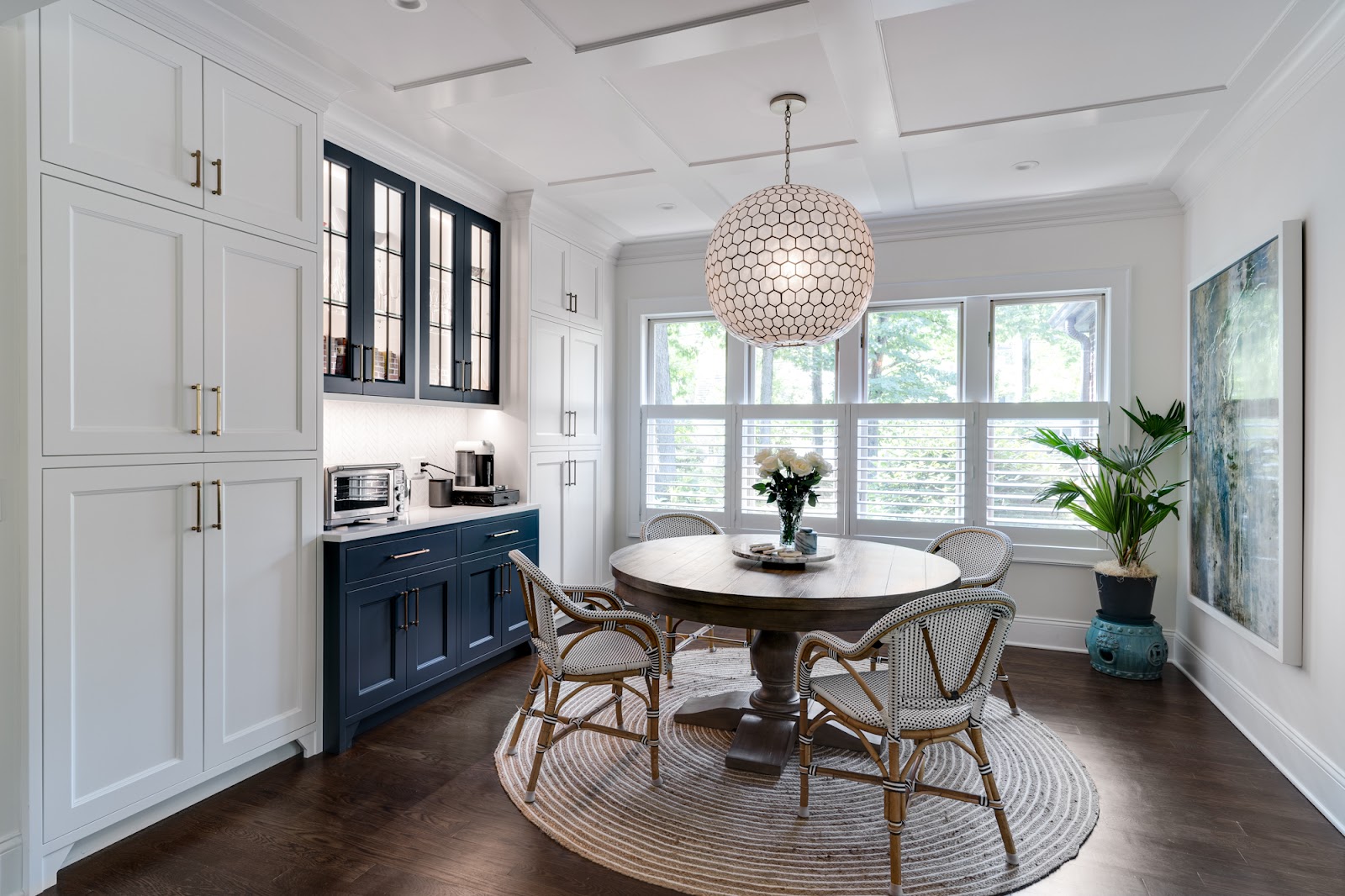 Breakfast nook with navy and white custom built-ins, coffered ceiling and round table
