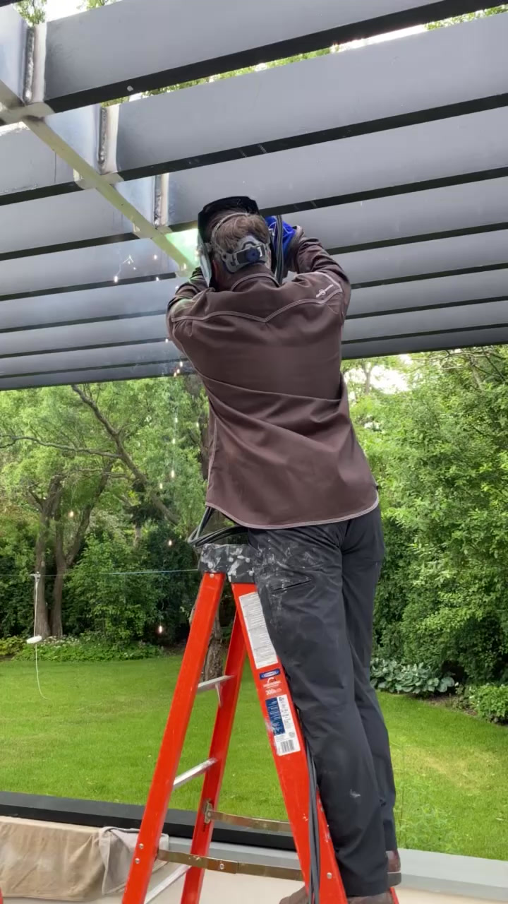 Welder fabricating a custom steel pergola on site